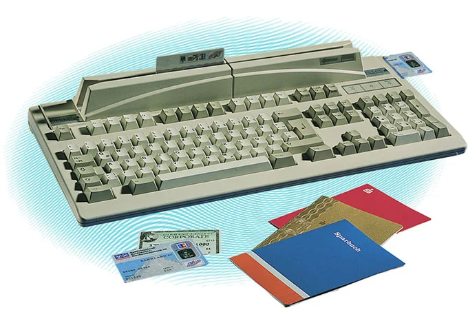 Beige DESKO Sicherheits-Tastatur mit integriertem Kartenleser, davor Ausweise und Kreditkarten auf hellem Hintergrund.