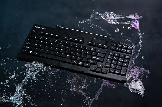 Robuste, wasserfeste Tastatur, die von spritzendem Wasser umgeben ist und ihre Widerstandsf&auml;higkeit gegen Fl&uuml;ssigkeiten zeigt.