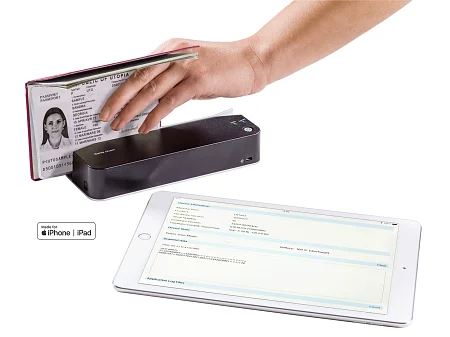 La mano coloca el pasaporte desplegado en el escáner móvil de documentos de identidad, los datos aparecen en paralelo en la pantalla de la tableta.