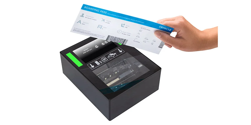 Hand h&auml;lt eine Bordkarte &uuml;ber einen kompakten Dokumentenscanner, der das Ticket durch Glasoberfl&auml;che digital erfasst.