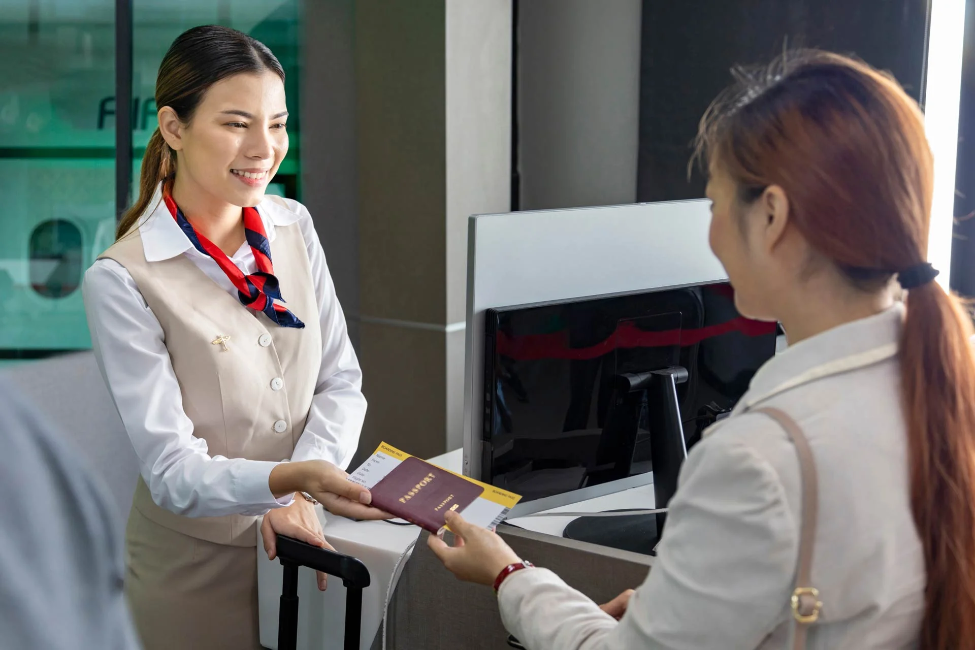 Friendly employee at the check-in counter takes a passenger's passport to carry out an identity check.