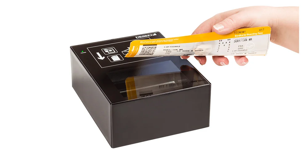 Hand h&auml;lt gelbe Bordkarte &uuml;ber einem kompakten DESKO-Dokumentenscanner mit Glasfl&auml;che.