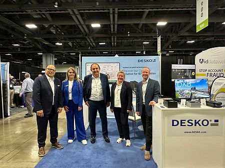 Five people stand at the DESKO stand, presenting ID authentication solutions in a large exhibition hall.