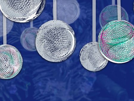Abstract, floating spherical structures made of fine lines in silver, green and pink against a deep blue, textured background.