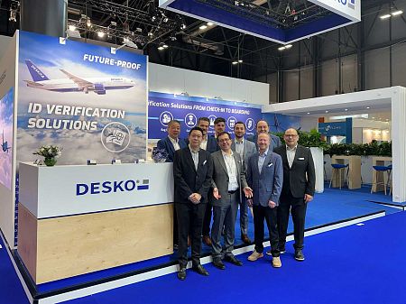 Fünf DESKO-Mitarbeiter stehen gemeinsam vor dem Messestand mit ID-Verifikationslösungen und großem Markenauftritt.
