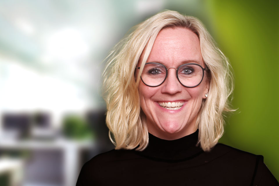 Blonde Frau die im Büro ist lacht in die Kamera.