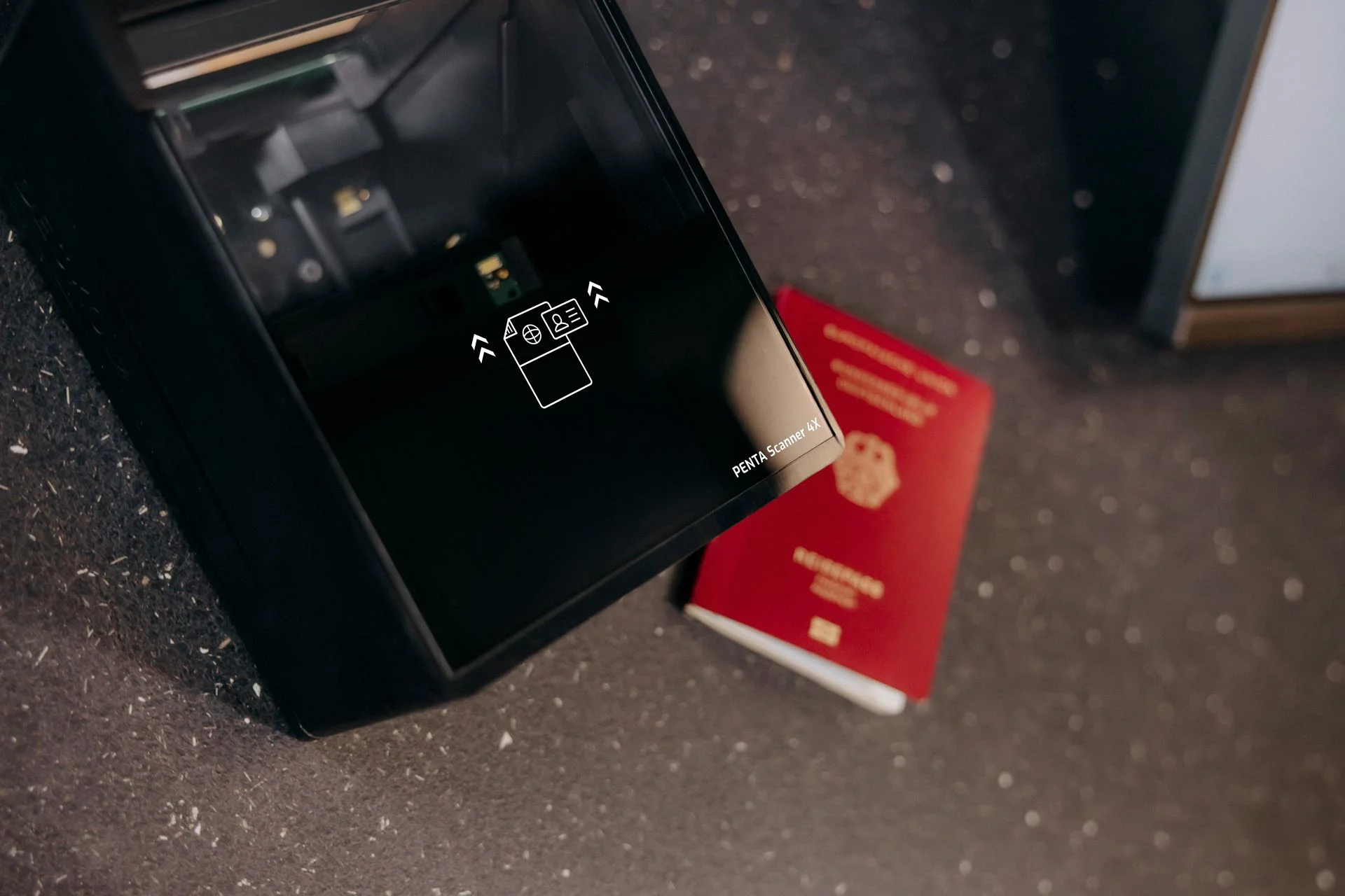 Esc&aacute;ner de pasaportes DESKO visto desde arriba, con un pasaporte al lado