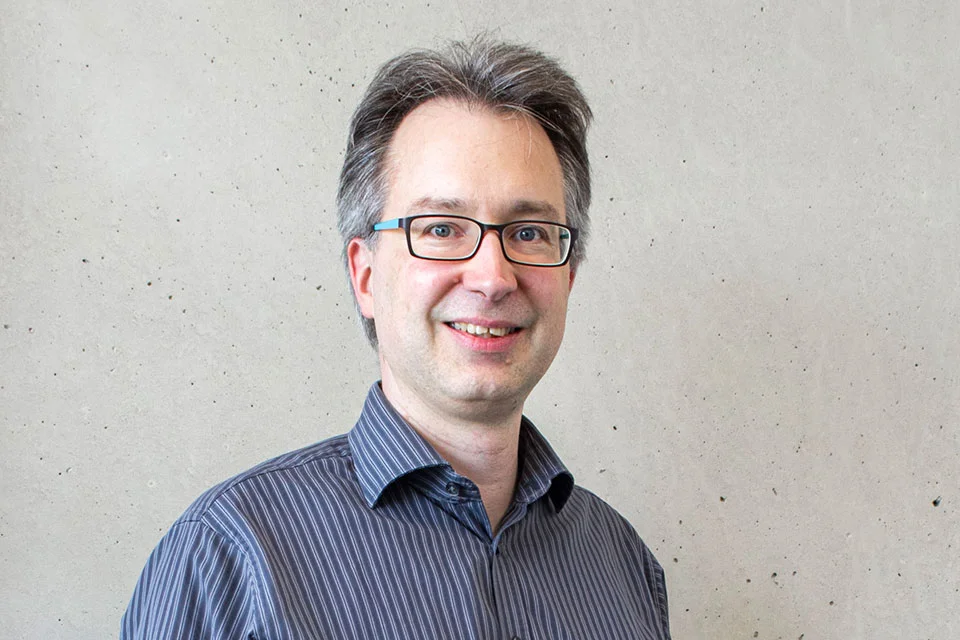 Portrait eines Mannes der eine Brille und ein gestreiftes Hemd tr&auml;gt