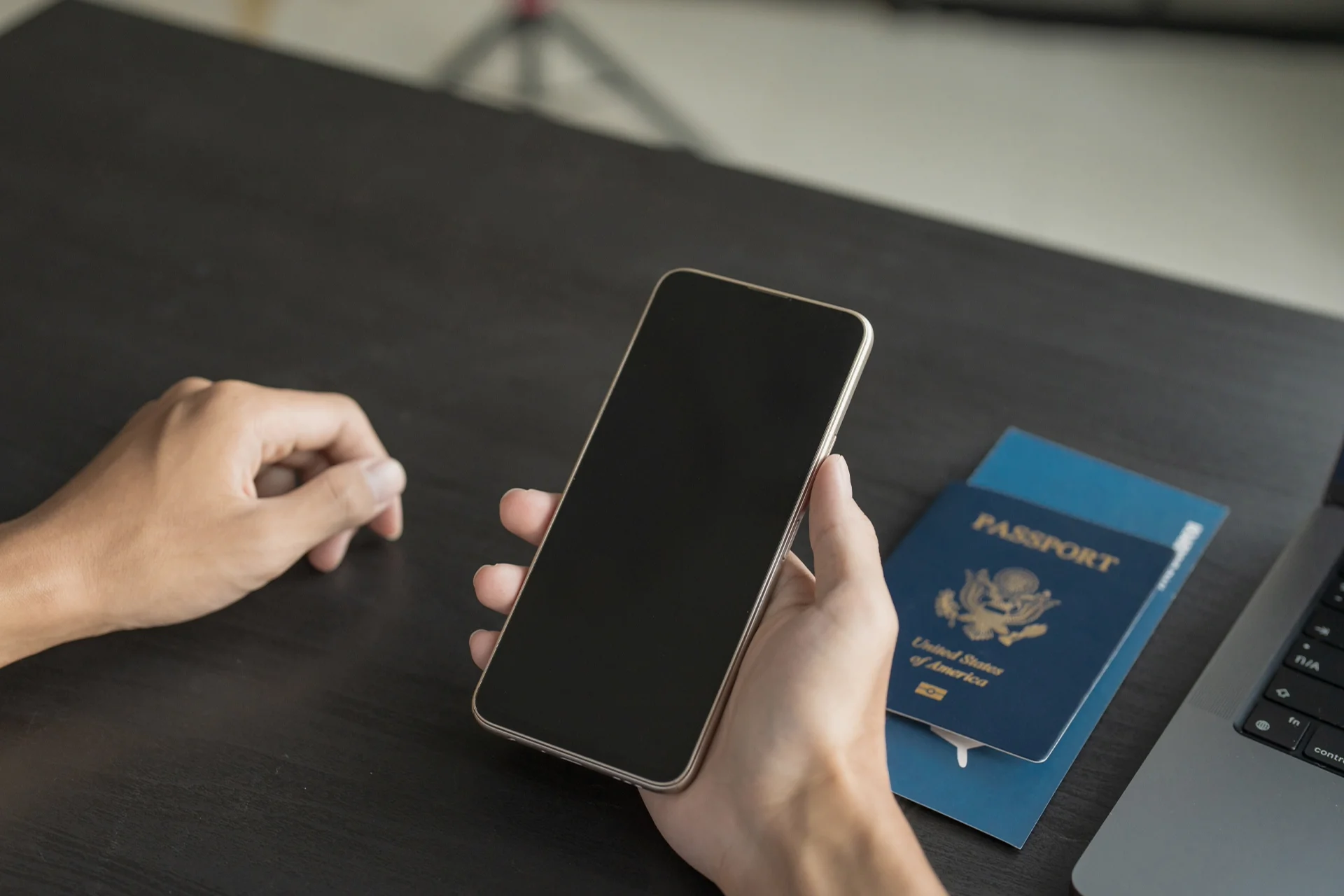 Mobiltelefon in der Hand, Ausweisdokumente auf dem Tisch