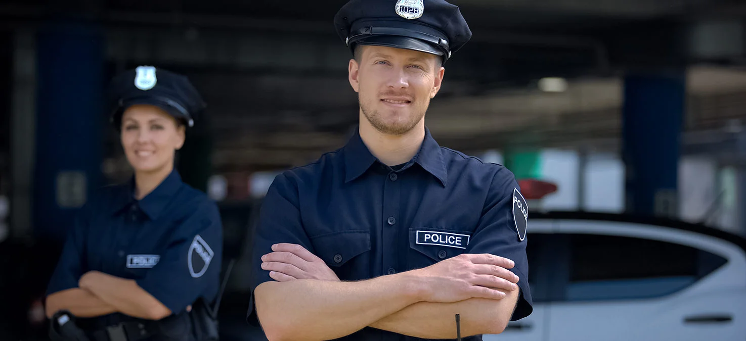 M&auml;nnlicher und weiblicher Polizist stehen vor Polizeiauto.