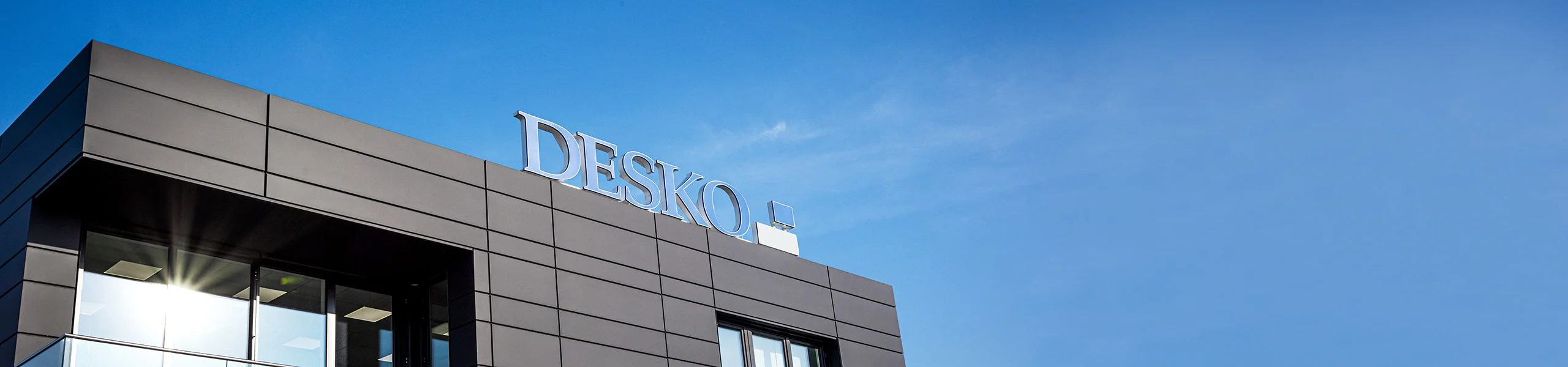 Moderna sede de la empresa DESKO con llamativo logotipo en la fachada sobre un cielo azul.