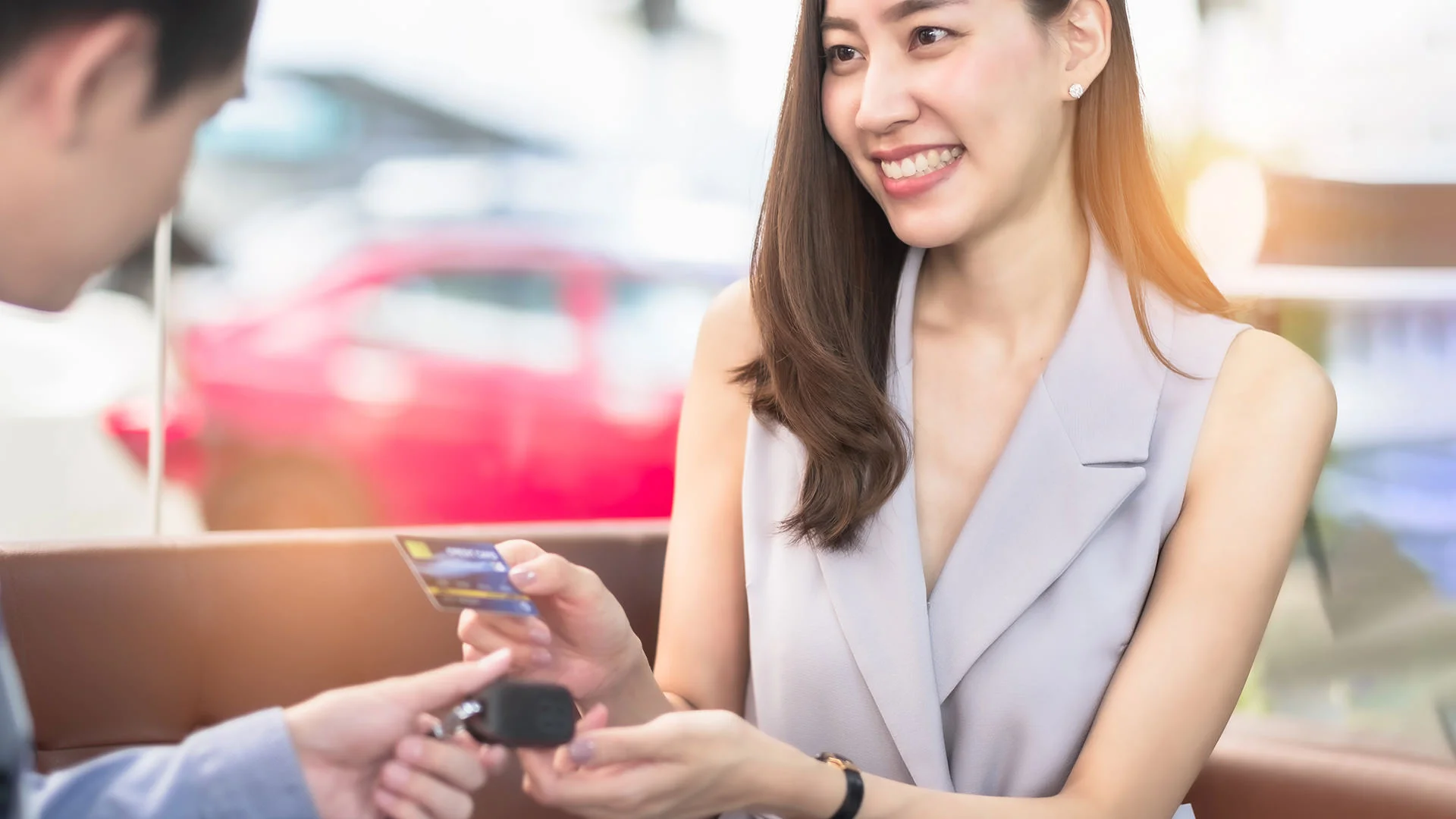 Une jeune femme re&ccedil;oit les cl&eacute;s d'une voiture au comptoir d'une agence de location.