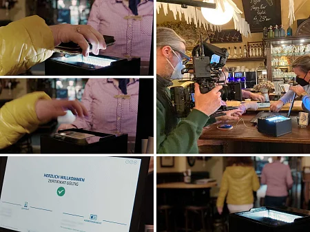 Une équipe de tournage documente un contrôle d'identité dans un bar : une personne scanne un document, l'écran affiche un certificat valide, les clients se servent au comptoir.