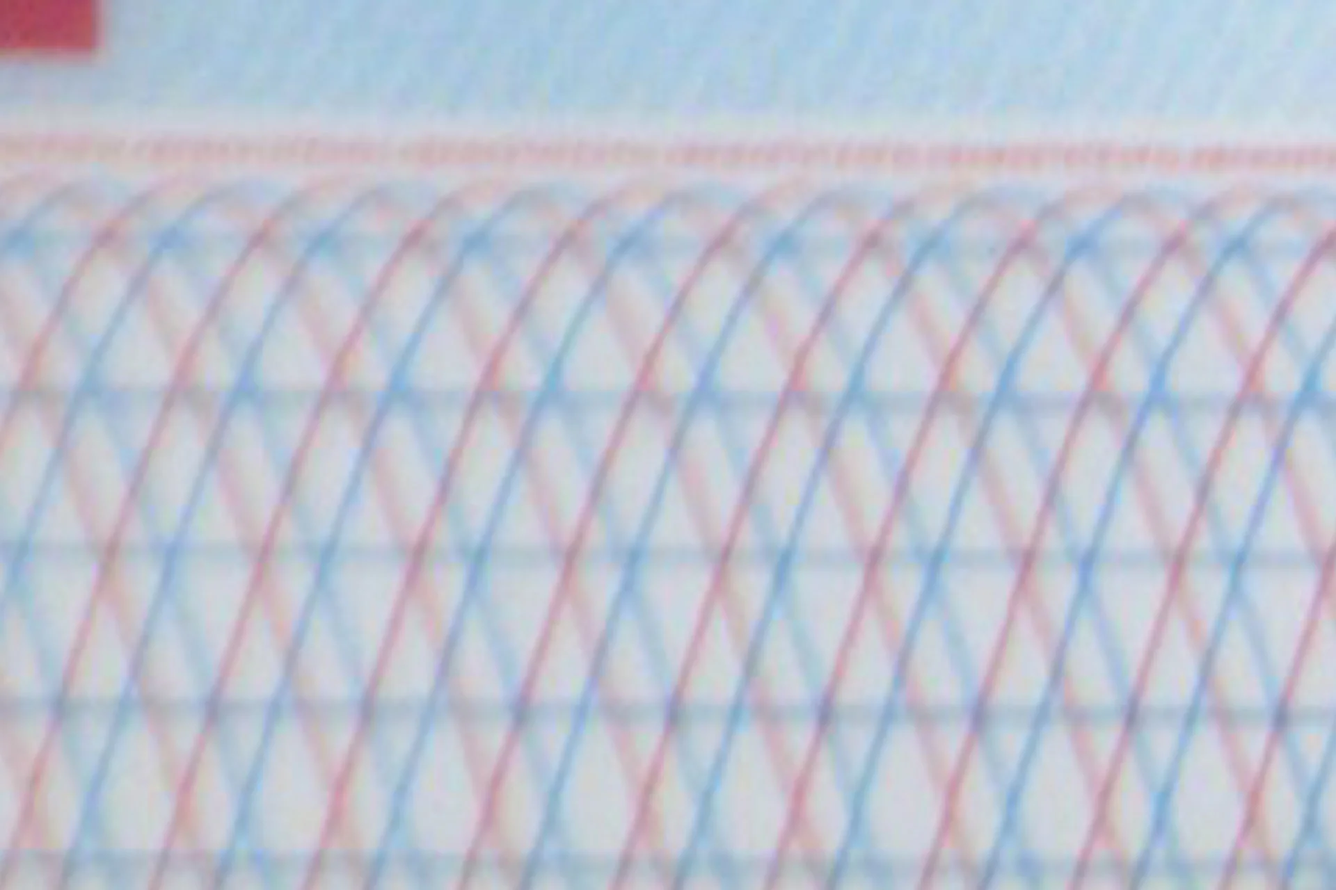 Macro image of a fine, multi-coloured guilloche security pattern with overlapping lines on document paper.